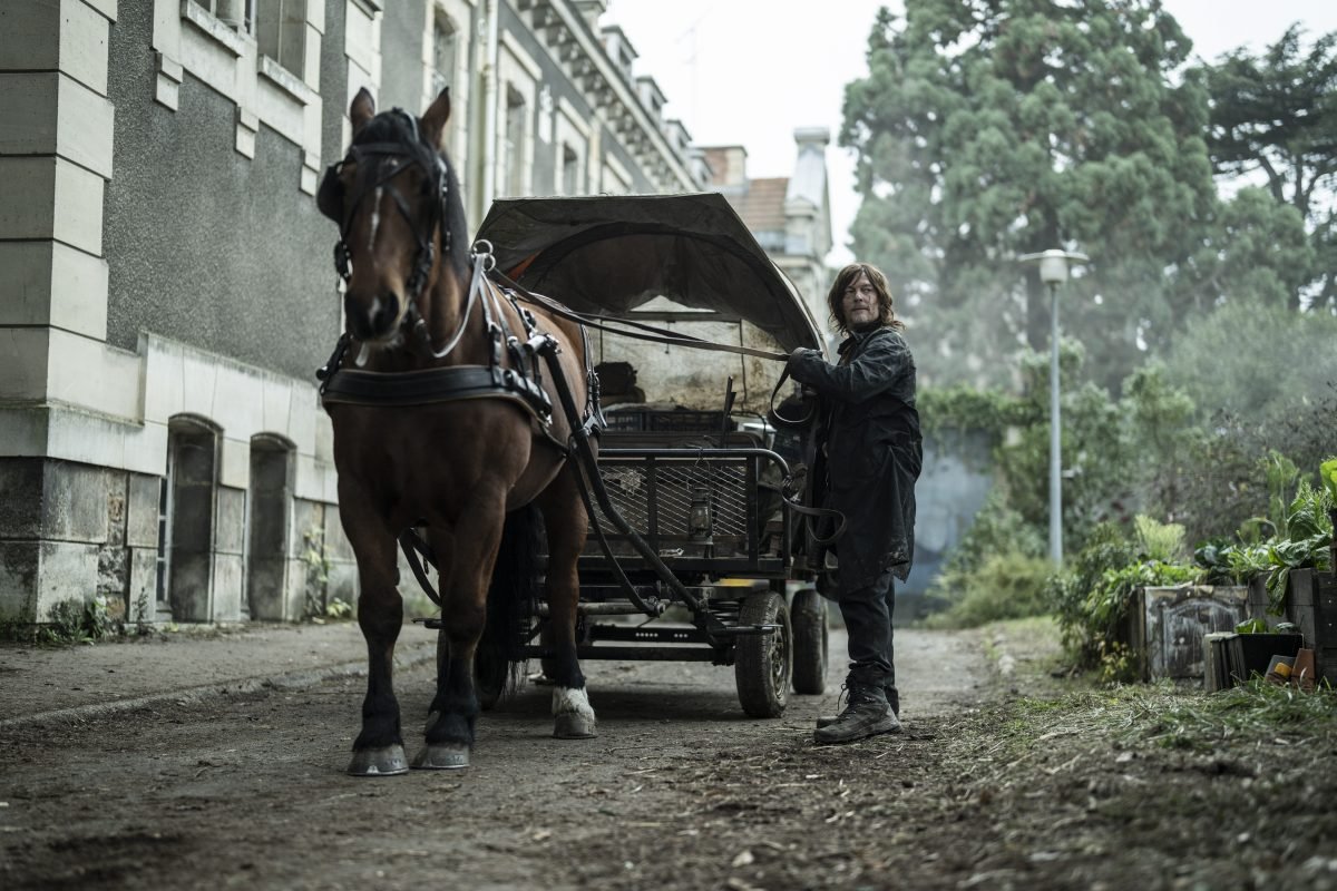daryl dixon stands beside a horse and cart