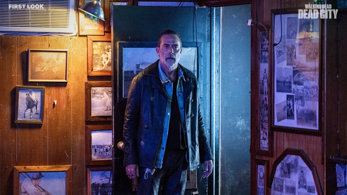 Negan stands in a room with a bunch of photos in Dead City 
