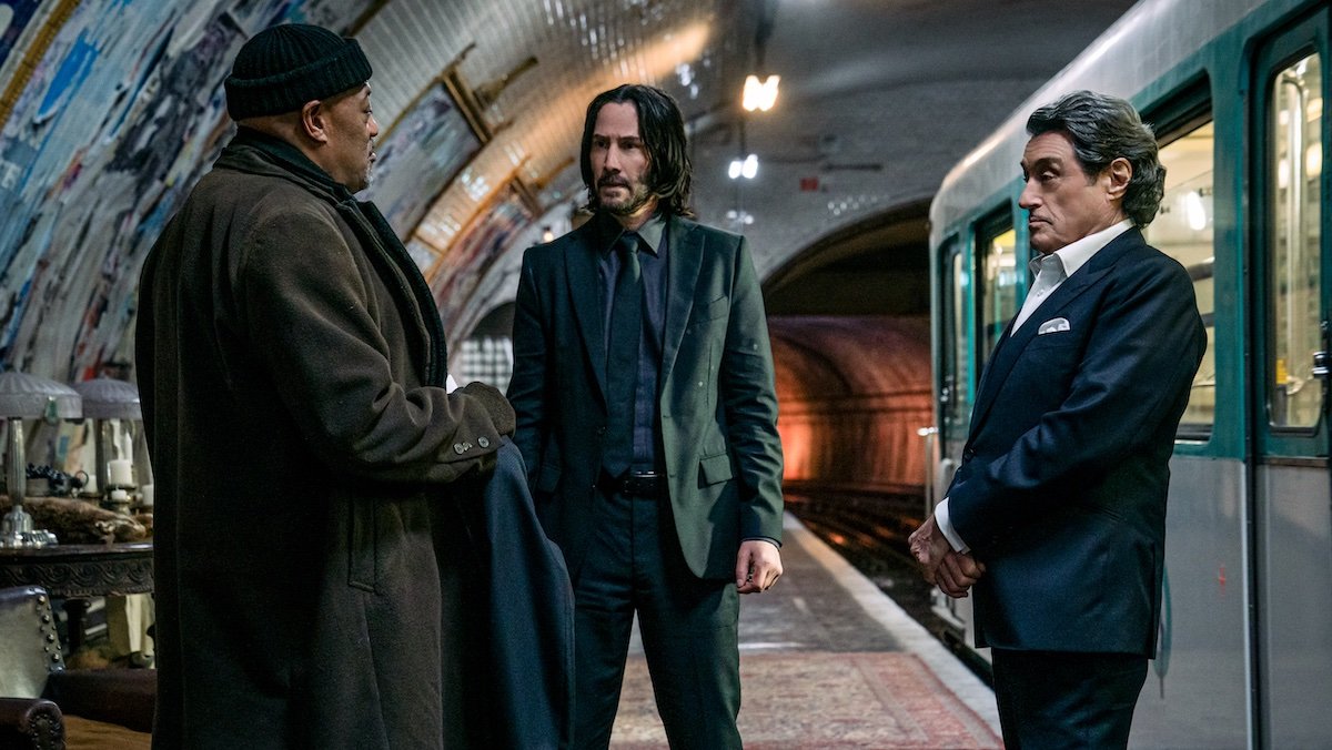 The Bowery King presents John Wick with a suit in a train station as Winston looks on in Chapter 4
