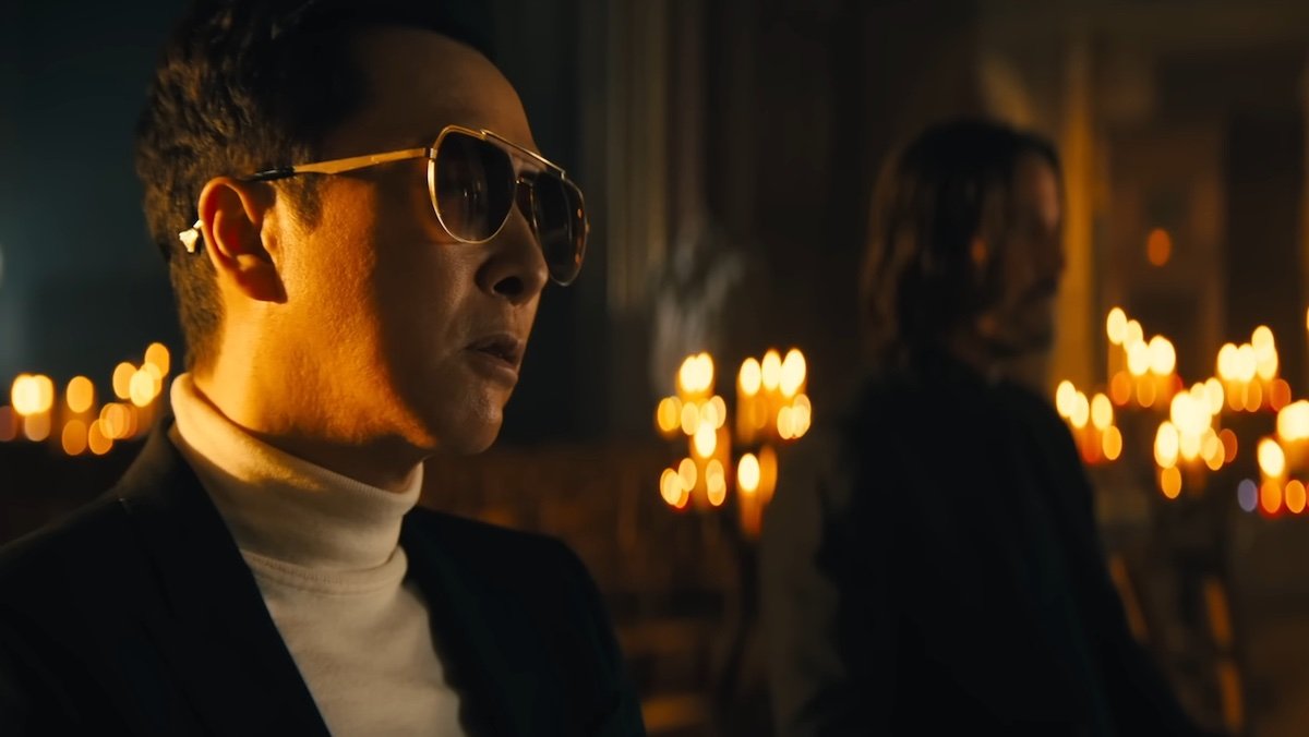 Caine in sunglasses sits in a church with John Wick opposite him in John Wick: Chapter 4
