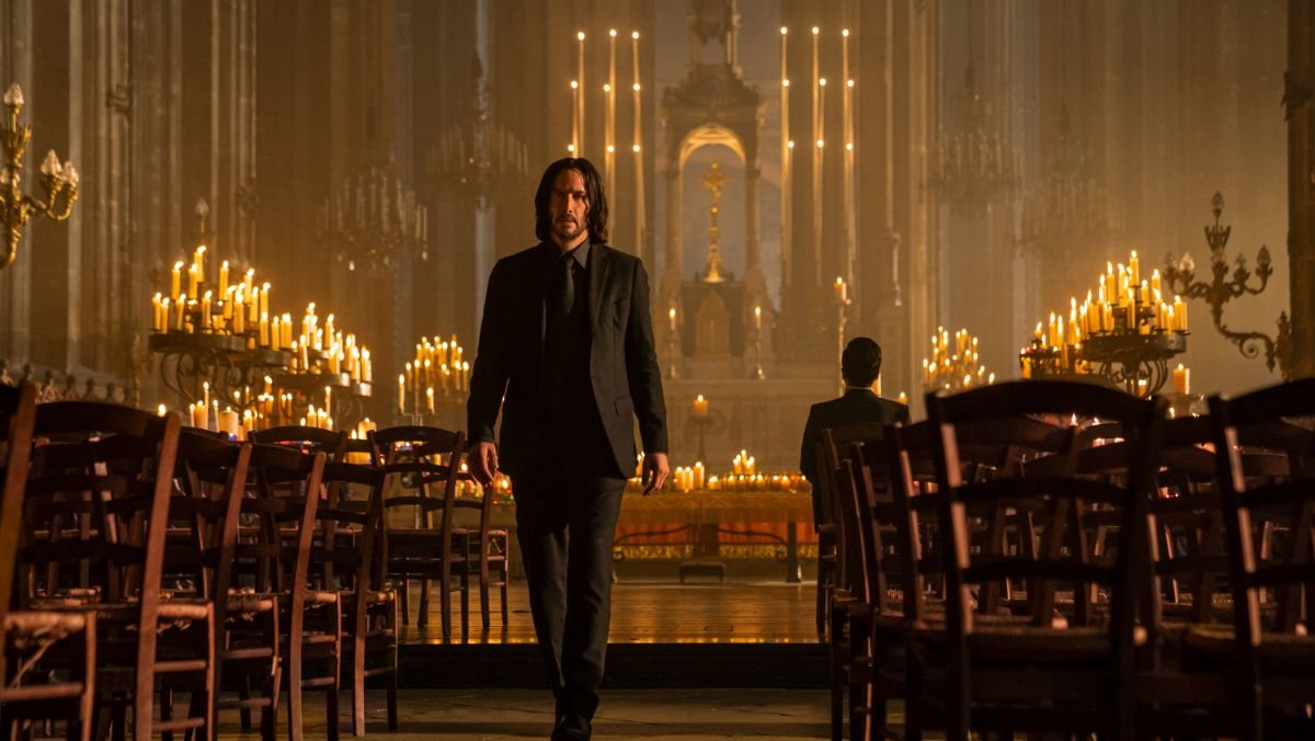 Keanu Reeves as John Wick walks out of a church full of candles wearing an all black suit in john wick chapter 4 trailer