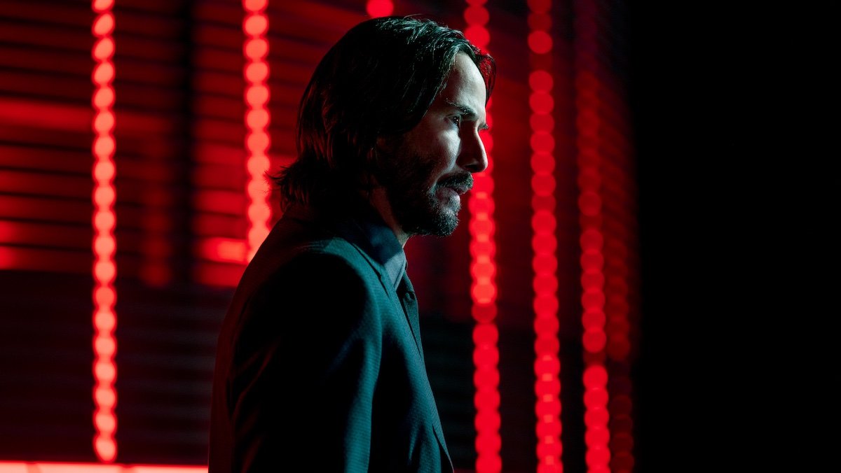 Keanu Reeves in John Wick: Chapter 4 against a red background