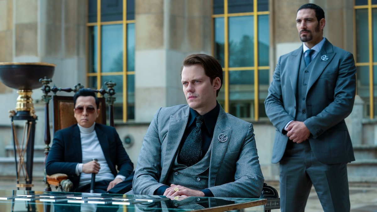 The Marquis sits at a table in front of Caine and his bodyguard in John Wick: Chapter 4