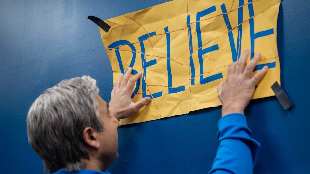 Nate puts up the taped together Believe sign on Ted Lasso