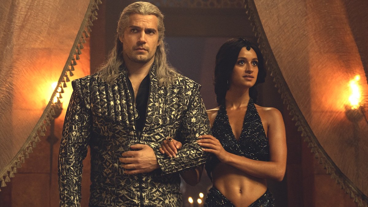 Yennefer holds Geralt's arm as they both enter a fancy party on The Witcher