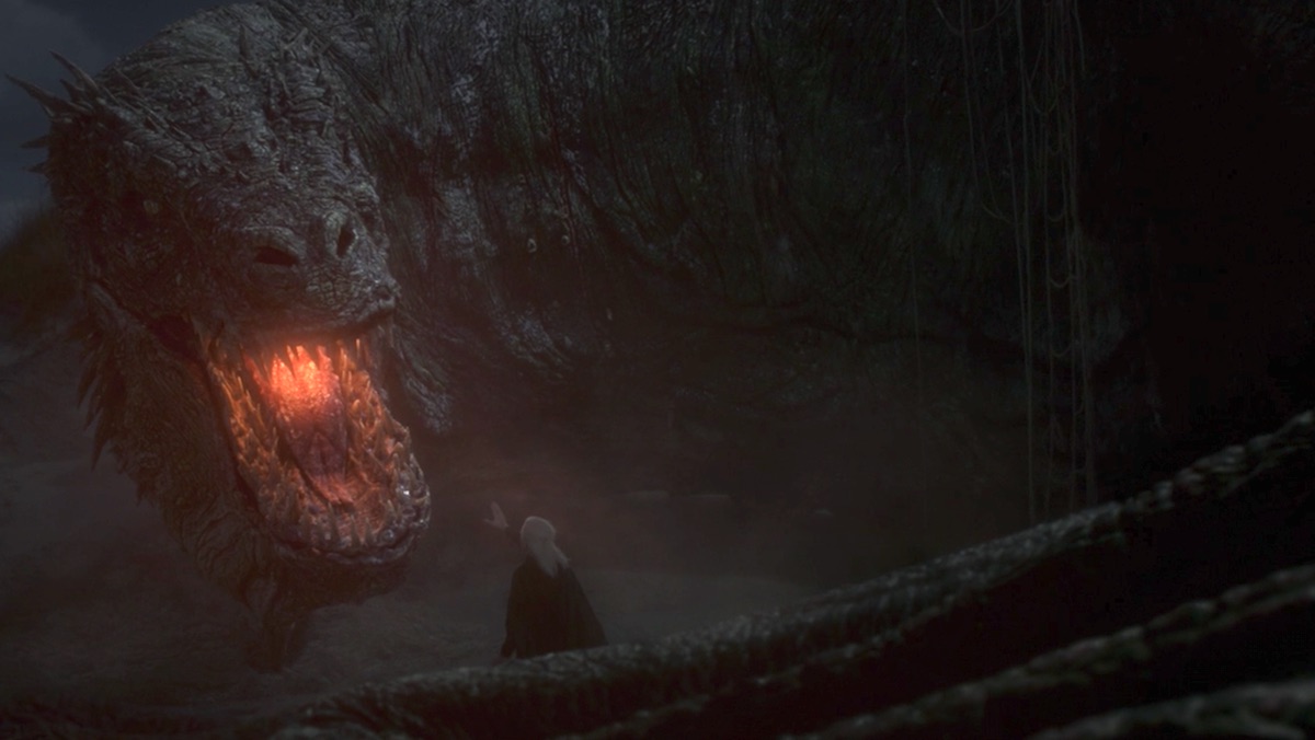 Aemond Targaryen stands near the giant dragon Vhagar who is lying down on House of the Dragon