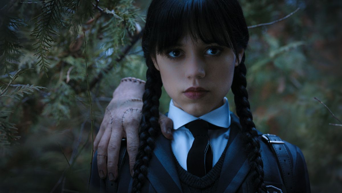 Wednesday Addams stands with thing on her shoulder in tv show powers