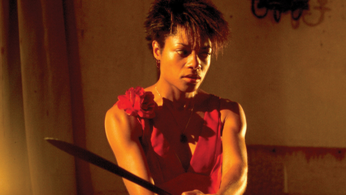 Selena from 28 Days Later holds a machete while wearing a red sleeveless dress